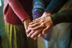 Elderly couple hold hands with their adult child