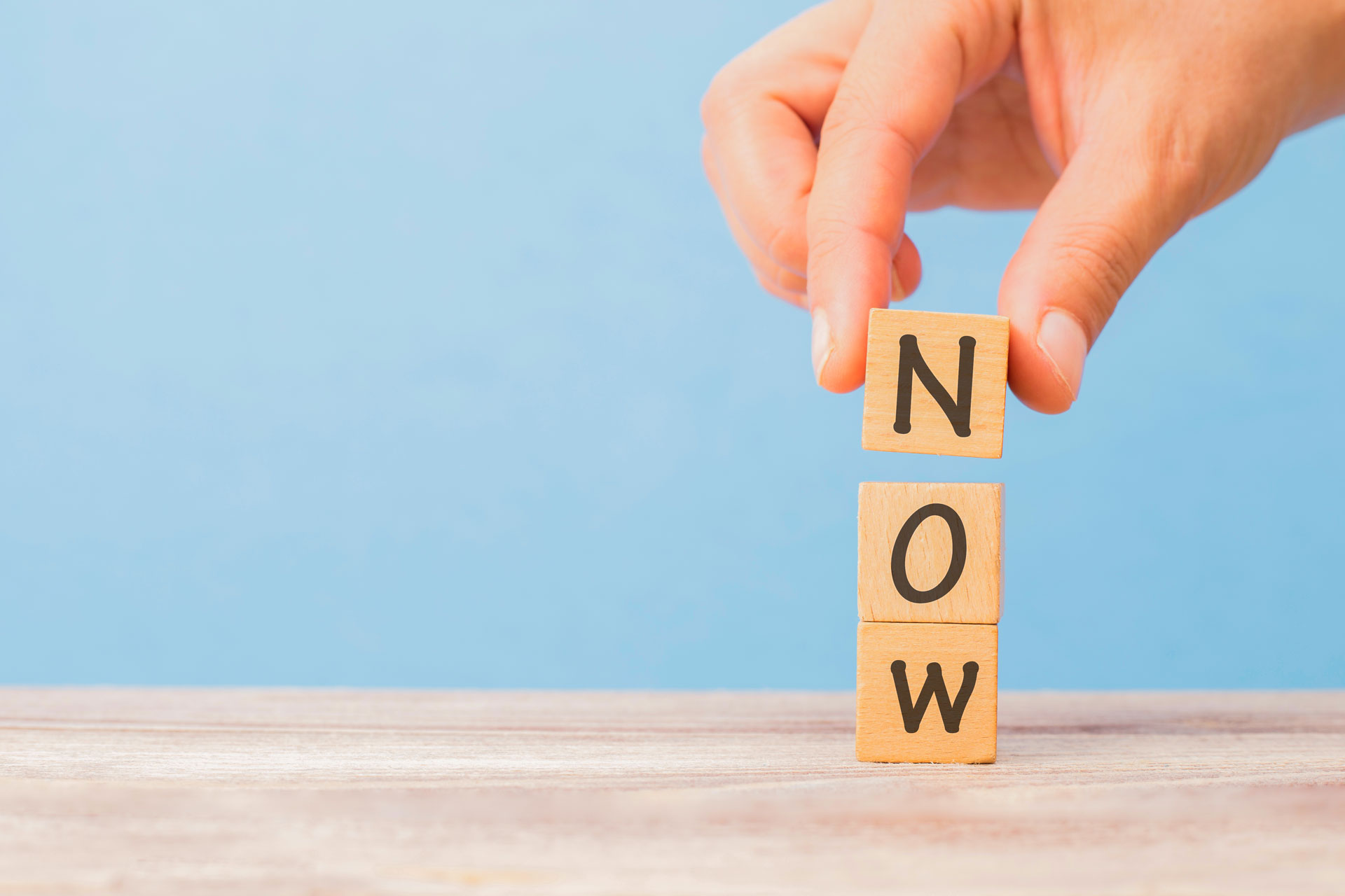 person stacks blocks on top of one another to spell now